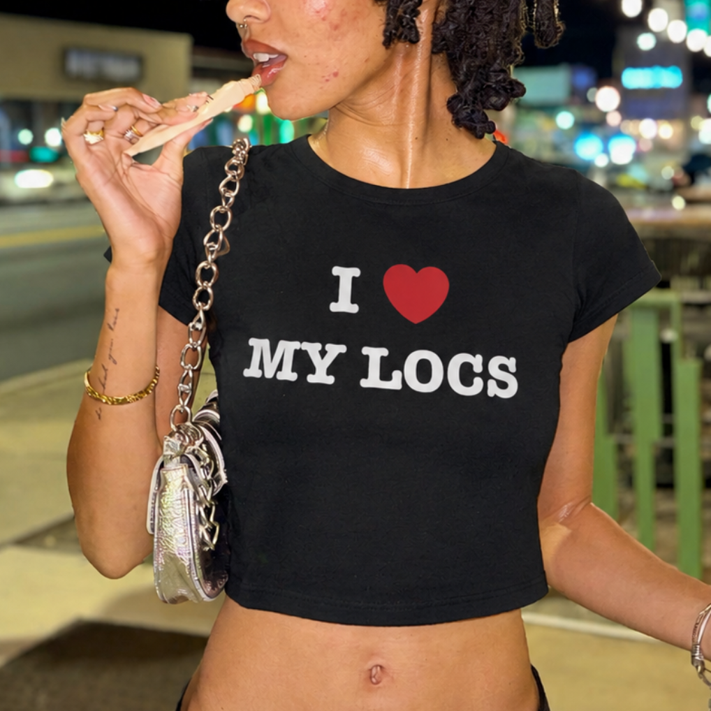 Woman wearing a black t-shirt with 'I ❤️ MY LOGS' text, eating outdoors at night.
