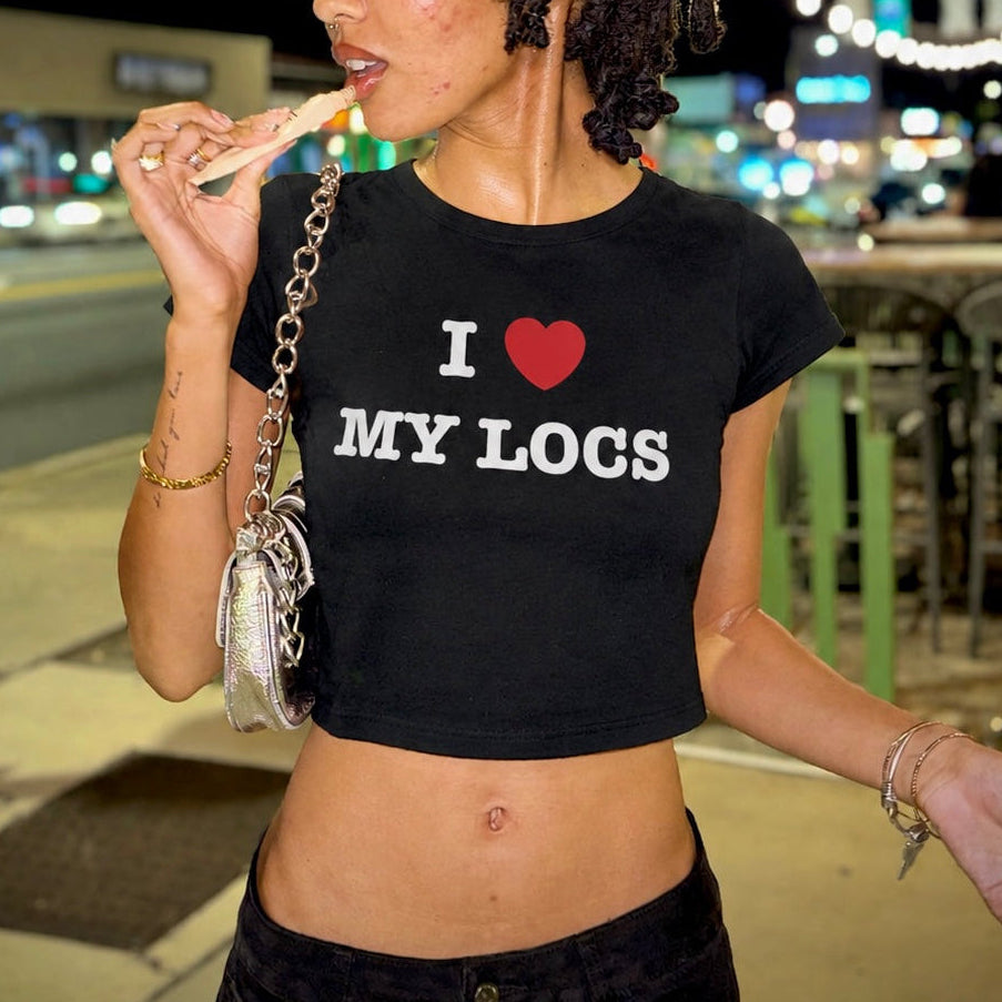 Woman wearing a black t-shirt with 'I ❤️ MY LOGS' text, eating outdoors at night.